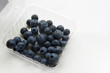 Organic heap of fresh pick blueberries in Polyethylene terephthalate (PET) plastic container on isolated white background with copy space. Low fat and calories for weight control