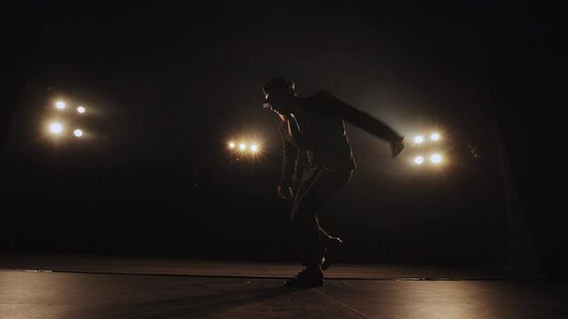 A man is emotionally dancing swing. The spotlight is shining on him. He's wearing a suit and hat. There's smoke all around it. 4K
