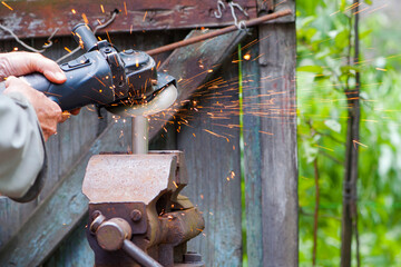 The worker cuts metal, steel with a grinder. the pipe is clamped in a vice, sparks fly. close-up, the hands of a man using a grinder to cut a pipe, bright flashes flying in different directions.