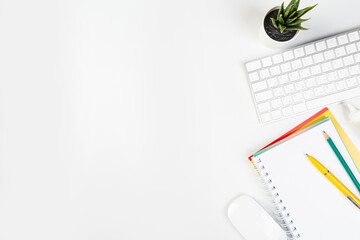 Flat lay, office table top view. Workspace with blank notebook, keyboard, stationery, pencil, succulent in a pot on a white background.