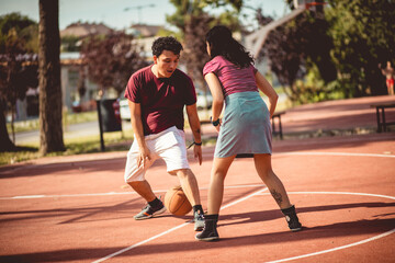 Fototapeta premium Young couple playing basketball on street court.