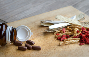Fototapeta na wymiar Bottled supplements and chinese herbs on wood table top. Modern medicine versus traditional herbs.