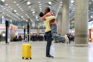 Happy meeting of loving couple after long time. African man and woman excited hugging in airport terminal after separation due to covid-19 lockdown and quarantine. Lovers reunion at airlines reopening