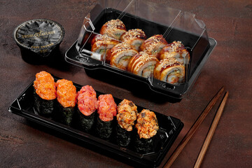 Sushi set of gunkan maki and rolls with eel in plastic boxes