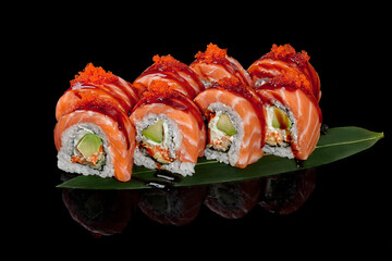 Philadelphia rolls with salmon and tobiko on bamboo leaf on black background