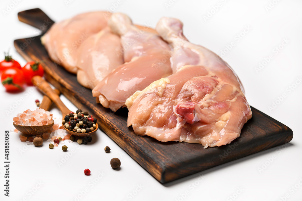 Wall mural skinless raw chicken thighs with ingredients for cooking on a wooden cutting board on white backgrou