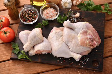 Fototapeta Fresh raw chicken thighs with ingredients for cooking on a wooden cutting board obraz