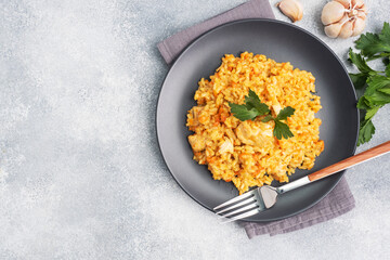 Delicious Asian pilaf, stewed rice with vegetables and chicken on a plate. gray concrete background. copy space.