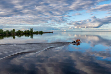 Fototapeta premium Sunset view of motorboat on Beloye lake. Belozersk, Vologda Oblast, Russia.