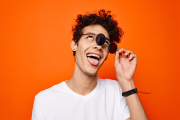 Cheerful guy in a white t-shirt dark glasses fashion orange background