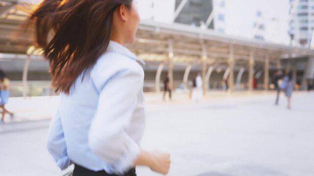 Late young Asian business woman rushing for work and running towards office building in downtown for an important meeting in city building background