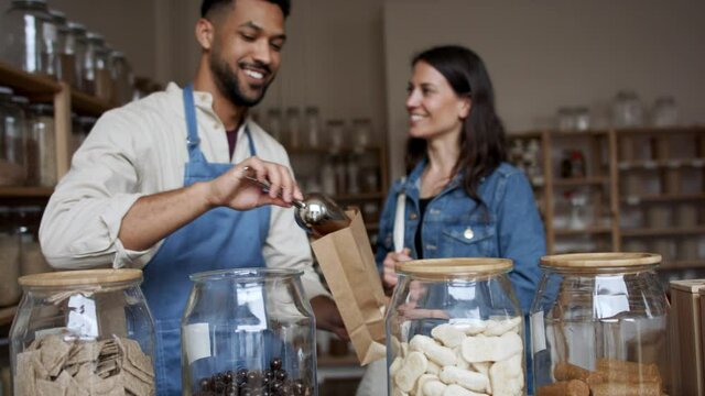 Woman buying almonds in chocolate in zero waste shop.