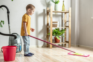 Little boy is cleaning the floor of a room using a mop. Concept of independence, help to parents,...