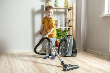 Fototapeta na wymiar Little child helps his parents in housework, cleaning the floor using a vacuum cleaner