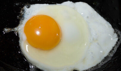 The process of cooking scrambled eggs. Chicken egg on a black background.