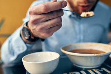 a man eats borscht with sour cream in a restaurant at a table in a cafe and a watch on his hand