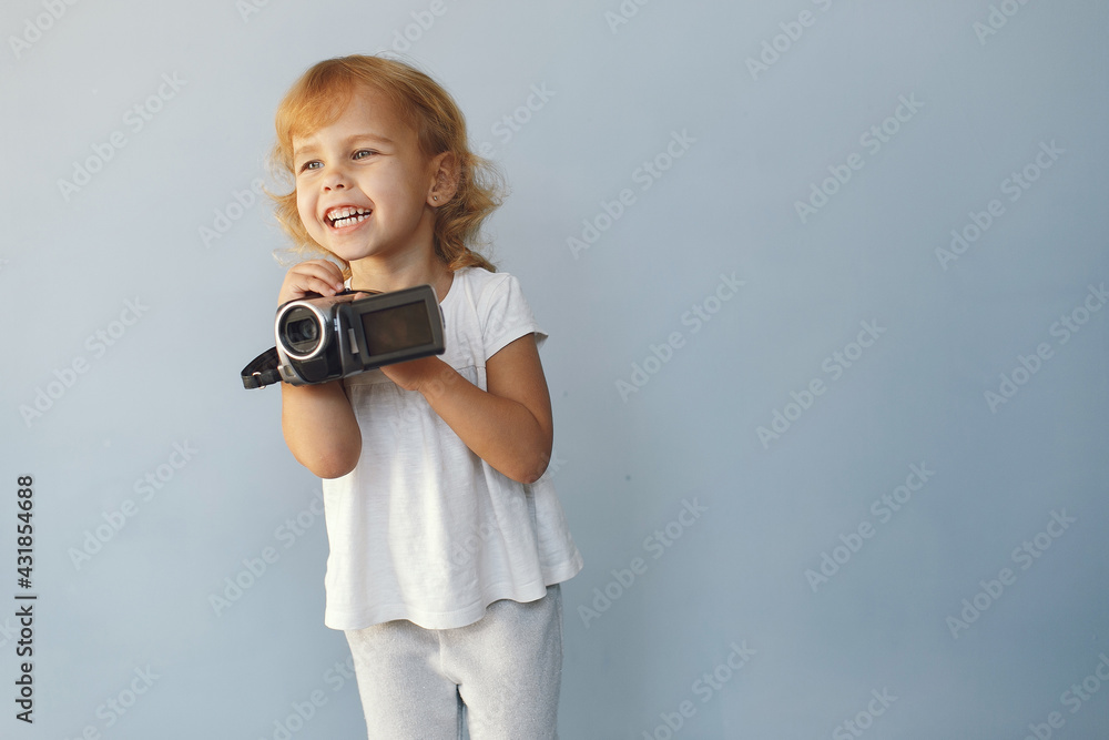 Wall mural Cute little girl sitting in a studio on a blue background