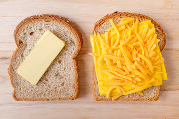 two slices of bread with butter and cheese which are ingredients used to make a grilled cheese sandwich