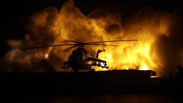 Silhouette of military helicopter ready to fly from conflict zone. Decorated night footage with helicopter starting in desert with foggy toned backlit. Selective focus. War concept