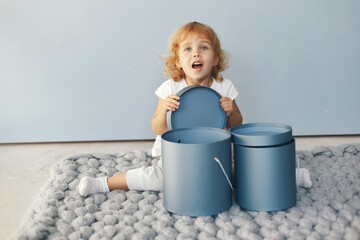 Naklejka premium Cute little girl sitting in a studio with presents box