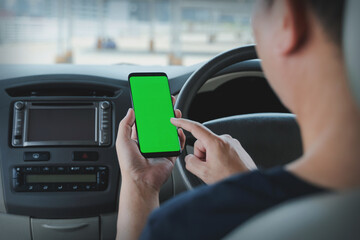 Mock up of man using mobile smart phone inside a car. Driver hand holding blank green screen smartphone, searching address and pin location via map navigator application, transportation