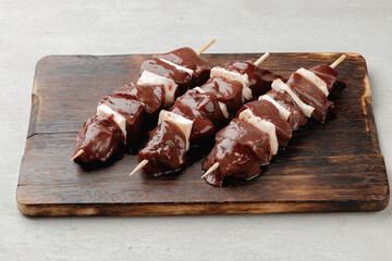 Raw beef liver on skewers on board