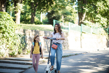 Happy day. Mother and daughter walking trough nature. Woman on scooter.