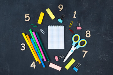Top view of school supplies on dark background. Text space