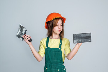 lets start. renovation and repair. using working tool. teen girl in helmet and boilersuit with spatula. child wear hard hat. kid builder on construction site. worker engineer. architect in workshop