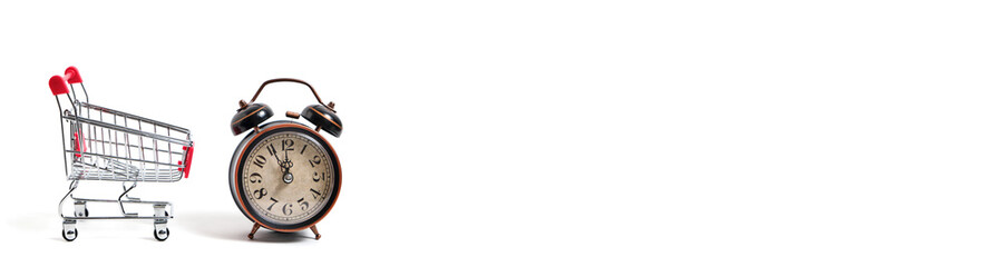 Retro alarm clock in shopping cart on white background.