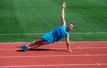 athlete train his core muscles. man doing stretching exercise on stadium. fitness gym outdoor. Full of energy. athletic guy training. sport. male strength and power. sportsman in side plank