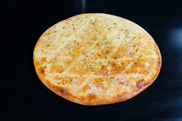 Sliced pizza on a black stone background, top view. Freshly baked focaccia with cheese