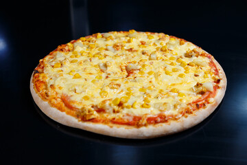Delicious Italian pizza with raw meat, tomatoes and olive oil on a dark concrete table. Top view with copy space.