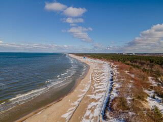 Aerial view of snowy Baltic sea coastline with dunes in one side and sea in another