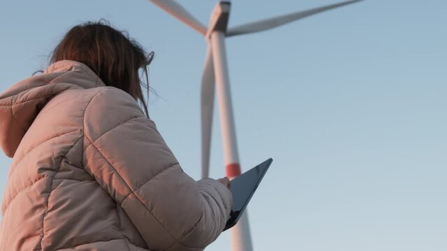 A wind turbine inspector standing with tablet and controls the system. Generation of electricity. 