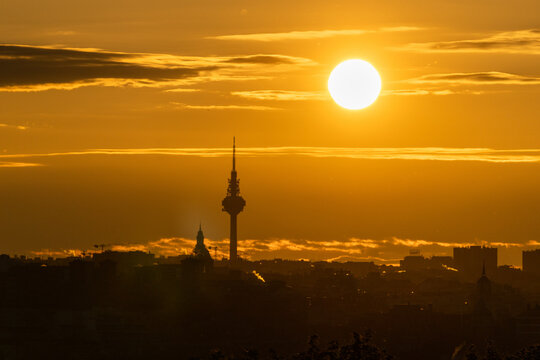 sunset over the city with big sun and tower of communications. torre españa in madrid