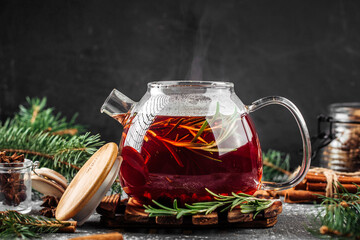 Glass kettle of fresh berry tea with rosemary on the decorated background