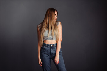 A girl with long hair looks stretched up on a gray background without retouching.