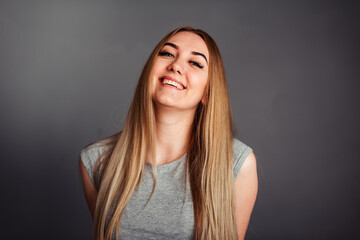 A girl with blue eyes looks piercingly into the frame, wrapping her hair in a gray background