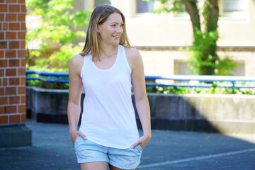 Attractive blonde woman in city wears white tank top with copy space or text space for print or design 