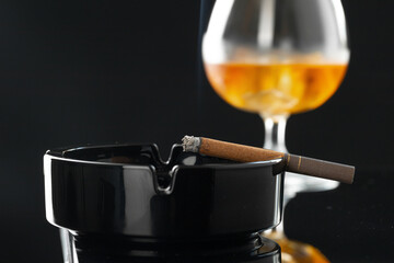 Close up of smoking cigar and whiskey glass on table