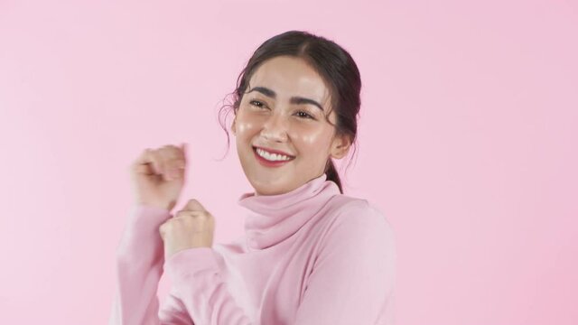 Beauty concept of 4k Resolution. Young Asian woman dancing with fun on a pink background.