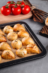 Fresh baked oriental pies samsa on a tray on decorated background
