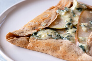 Galette bretonne with pear and gorgonzola cheese. Large buckwheat crepe stuffed with various savory fillings. Selective focus.