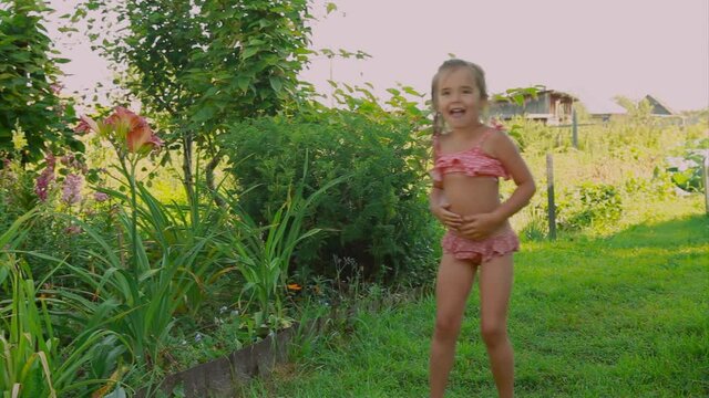 little girl in a swimsuit dancing in nature