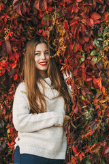 Happy woman is laying upon a wall of red ivy leaves.
