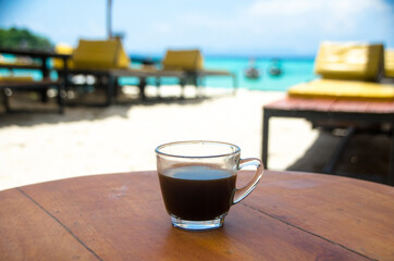 Black coffee on the wooden table, beachside, travel concept , nature light. Thailand