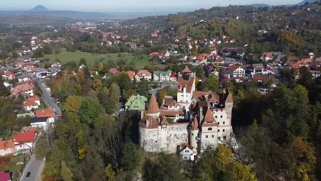 The famous medieval Bran Castle , the residence of count Dracula , situated on a hill in Bran County , Transylvania , Romania , aerial drone footage  , autumn season.