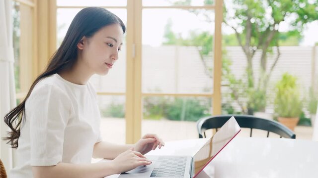 部屋でパソコンを使う女性　リモートワーク　テレワーク