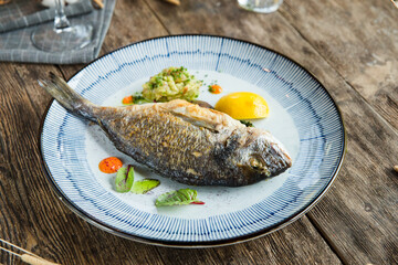 Gourmet roasted dorada fish on a beautiful plate on the wooden table
